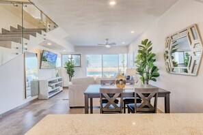 Open concept kitchen, dining and living room overlooking grass, beach and lagoon