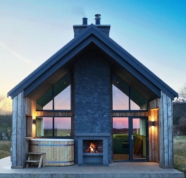 Exterior image of hottub and open fireplace under canopy