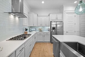 A sleek, fully equipped kitchen featuring stainless steel appliances, white cabinetry, and a spacious island.