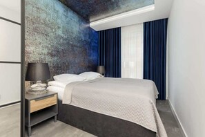 Elegant bedroom with a textured blue accent wall, white bedding, and soft lighting.
