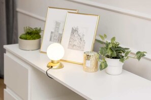 Elegant white console table adorned with framed artwork, greenery, and a golden lamp.