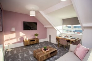 A wooden centre table and TV console add a touch of rustic charm, while fresh flowers breathe life into the space