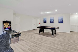 Enjoy endless fun in this spacious game room featuring an air hockey table and arcade game, perfect for family gatherings.