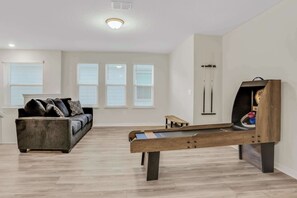 Enjoy fun-filled evenings in this spacious game room with shuffleboard and cozy seating, perfect for large gatherings.
