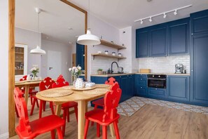 Kitchenette with an induction hob, refrigerator, freezer, dishwasher, oven, electric kettle, coffee maker, toaster, washing machine and dining table with chairs

