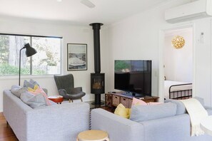 The living area features a cosy wood heater along with two sofas to settle into with a movie.
