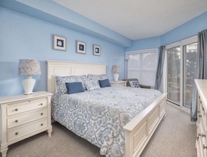 Master bedroom with bathroom and sliders to patio. King sized bed.
