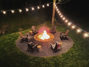 Back yard firepit with Adirondack chair seating for 6 with string lights.