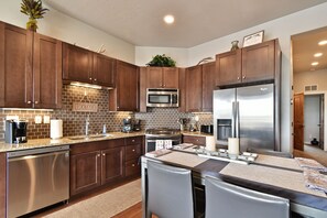 Modern kitchen featuring sleek stainless steel appliances, rich wood cabinetry, granite countertops, and a stylish tiled backsplash. Perfectly equipped for cooking and gathering, with a cozy dining nook for casual meals or morning coffee.