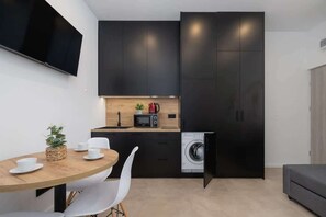 A compact, elegant dining area with a round wooden table and two chairs, seamlessly integrated into the minimalist black kitchen design.
