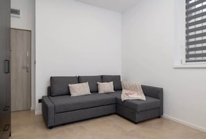 A cozy sleeping nook with a soft gray couch that doubles as a bed, complemented by a wardrobe for convenient storage.

