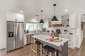 Fully equipped kitchen stocked with your basic cooking essentials, stainless steel appliances, and bar seating.