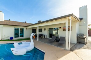 Private yard with sparkling pool, sun loungers, cornhole, and outdoor covered patio with BBQ grill.