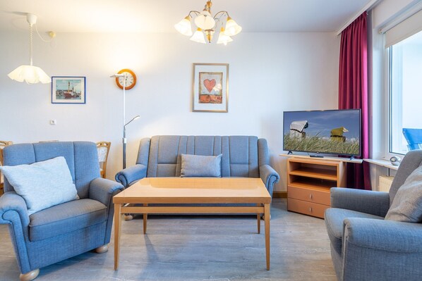 Sofa mit Sessel und Flachbild-TV.