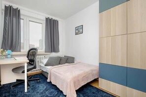 A well-lit workspace featuring a wooden desk, a comfortable chair, and a large wardrobe with blue and beige panels, perfect for a productive environment.


