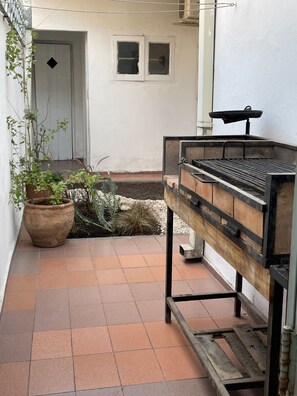 Parrilla con utensilios en patio interno.