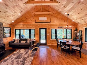 Main living space with wood burning fireplace, TV, Air Conditioning mini-split, walkout to main deck area and adjacent to dining and kitchen areas