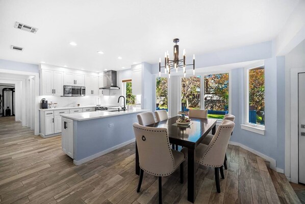 Immerse yourself at an inviting table, adorned with details. The soft ambiance envelops you, sparking anticipation. Here, a fully stocked chef's kitchen stands ready for your culinary experience.