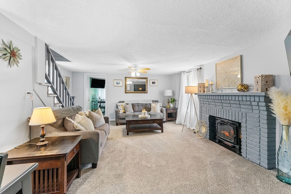 Relax in our cozy living room that boasts a 65" Smart Tv and Electric wood stove