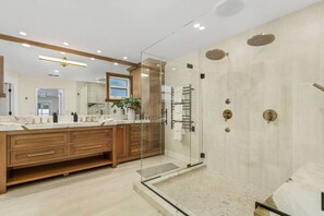 A primary bathroom with rainfall showers, soaking tub and his/hers vanity. Heated floors!