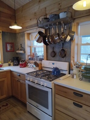 Full size refrigerator, range, microwave and gas grill outside on covered patio.