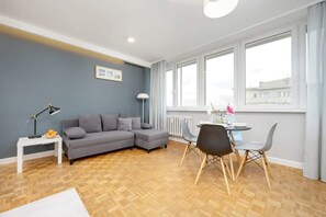 Cozy living room with a spacious gray sofa, minimalist decor, and warm natural lighting.
