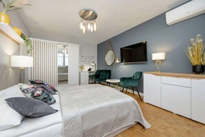 Another view of the bedroom, featuring a large mirror, decorative lighting, and a sleek white dresser.
