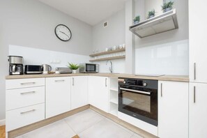 Modern kitchen with white cabinetry, black appliances, and a sleek wooden countertop.
