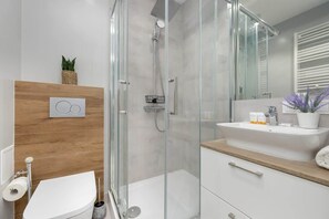 Elegant bathroom with a glass-enclosed shower, wooden accents, and a floating vanity.

