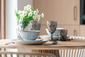 A close-up of a dining table set with elegant dishes, a flower arrangement, and glassware.

