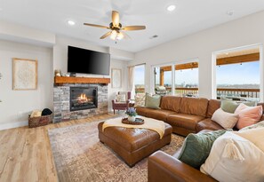 The cozy living room is ideal for family gatherings, complete with a fireplace and large windows that bring the outside in.