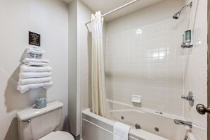 Unwind in our practical bathroom, featuring a one-person jetted bathtub, perfect for relaxation after a day's adventures. Benefit from the privacy of a separate toilet area. With its efficient layout, tile details, and essential amenities, this bathroom offers a comfortable retreat, adding a touch of convenience to your stay.