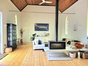 Open plan living room with soaring ceilings and double sided wood burner