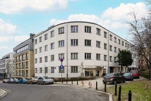 The exterior of a classic apartment building with curved architecture and a quiet street.

