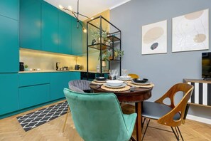 An open-plan kitchen and dining area with bold turquoise cabinets and elegant decor.

