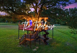 The treehouse emits a cozy glow as evening falls, offering a perfect retreat to relax and enjoy the tranquility of the surroundings.