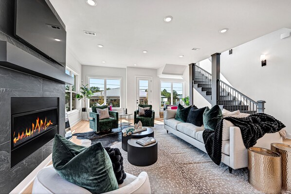 Bright first floor living area with a illuminated color-changing gas fireplace.