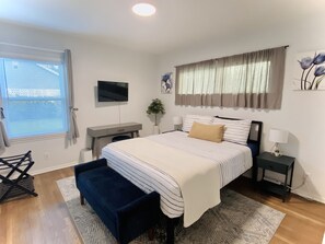 Main bedroom facing the backyard with TV/Roku, vanity desk, and individual AC. 