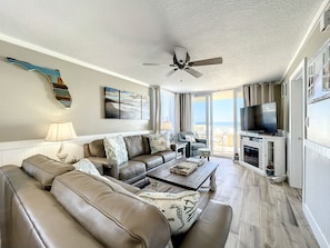 This beautifully decorated living room features plush seating, modern décor, and large windows offering breathtaking ocean views, perfect for relaxation and enjoying coastal vibes.