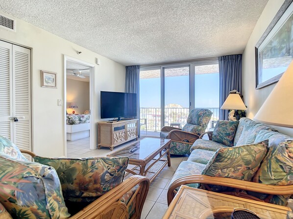 Comfortable seating with tropical accents and large windows showcasing stunning views.