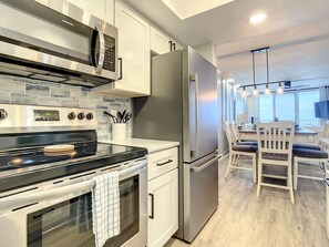 Fully equipped kitchen with stainless steel appliances, sleek backsplash, and a bright, open layout.