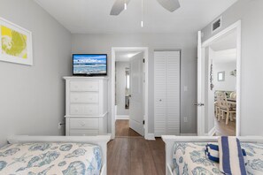 A charming twin bedroom featuring ocean-inspired bedding and a TV for entertainment.