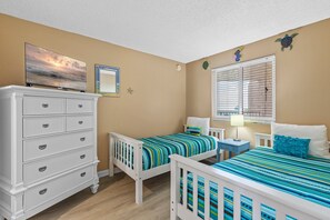 Cheerful twin bedroom with colorful bedding, coastal decor, and a flat-screen TV for comfort and entertainment.