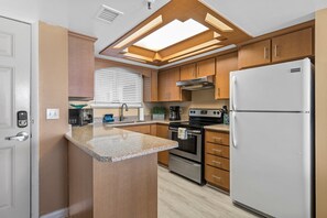 Contemporary kitchen featuring sleek appliances, wooden cabinetry, and beautiful under-cabinet lighting.