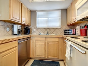 Compact kitchen featuring ample counter space, stainless steel dishwasher, and all essentials for preparing meals.