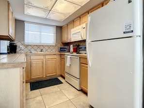 Functional kitchen with all the essentials, featuring a stove, refrigerator, and ample counter space.