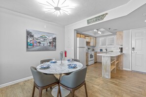 Bright dining space with modern lighting, a cozy round table, and a fully equipped kitchen featuring rustic wood accents.