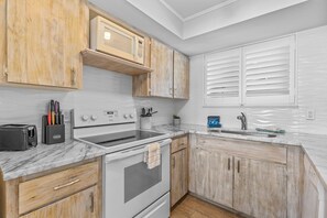 Beautifully designed kitchen with detailed wood cabinetry, modern appliances, and marble-style counters for a stylish cooking experience.