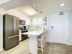 Fully equipped kitchen with stainless steel appliances, bar seating, and ample countertop space for dining and prep.