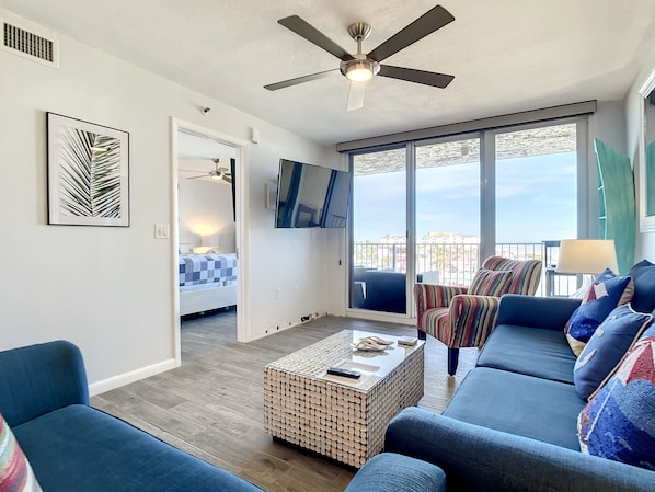 Bright and stylish living area featuring comfortable seating, a flat-screen TV, and access to a private balcony.
